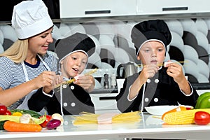 A family of cooks.Mother and children prepares spaghetti in kitchen.