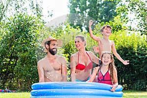 Family cooling down splashing water in garden pool
