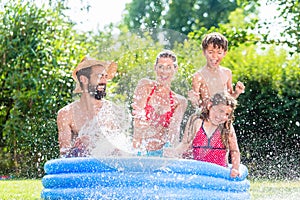 Family cooling down splashing water in garden pool