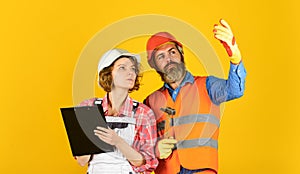 Family counting finances for renovation. Couple looking at documents. Woman and man wear safety hard hat. Redevelopment