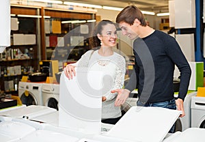 Family couple choosing new clothes washer in supermarket