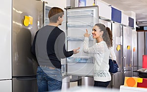 Family couple choosing new refrigerator in hypermarket
