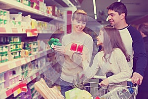 Family couple and girl choosing sweet pudding and smiling