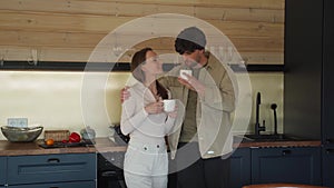 Family couple has breakfast together in their new home - young couple smiling while drinking and eating in the kitchen