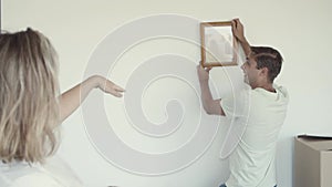 Family couple and kid hanging picture frame on wall