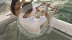 Family couple kisses sitting on trampoline net of yacht