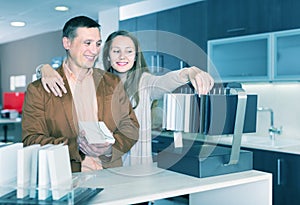 Family couple looking at kitchen tabletop in furniture worksho