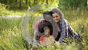 Family couple spending their free time with little daughter, relaxing in park