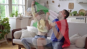 Family couple of sports fans at home with the flag of Italy. Football fans of the Italian national team are watching TV