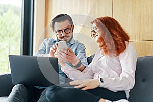 Family couple using laptop and smartphone for reading and discussing morning news or online work