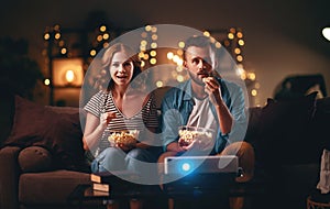 Family couple watching television projector at home on sofa