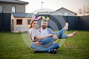 family couple wearing bunny ears celebrating easter. husband holding his wife in his arms