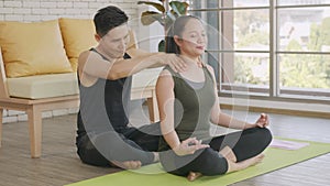 Family couple, woman doing YOGA sitting meditating on lotus pose workout at home and the man massage shoulder