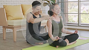 Family couple, woman doing YOGA sitting meditating on lotus pose workout at home and the man massage shoulder