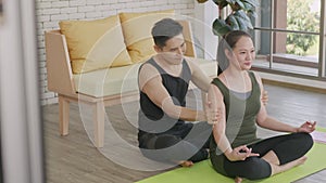 Family couple, woman doing YOGA sitting meditating on lotus pose workout at home and the man massage shoulder