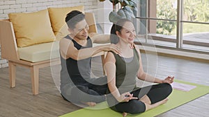 Family couple, woman doing YOGA sitting meditating on lotus pose workout at home and the man massage shoulder