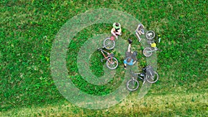 Family cycling on bikes aerial view from above, happy active parents with child have fun and relax on grass, family sport