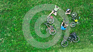 Family cycling on bikes outdoors aerial view from above, active parents with child have fun and relax on grass, family sport