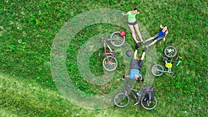 Family cycling on bikes outdoors aerial view from above, active parents with child have fun and relax on grass, family sport