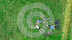 Family cycling on bikes outdoors aerial view from above, happy active parents with child have fun and relax on grass