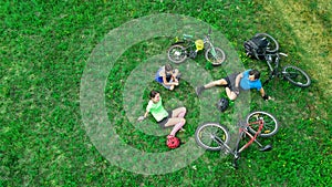 Family cycling on bikes outdoors aerial view from above, happy active parents with child have fun and relax on grass