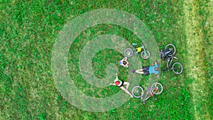 Family cycling on bikes outdoors aerial view from above, happy active parents with child have fun and relax on grass