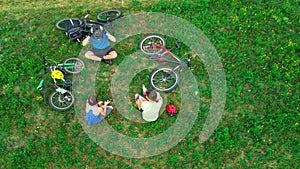 Family cycling on bikes outdoors aerial view from above, happy active parents with child have fun and relax on grass, family sport