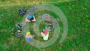 Family cycling on bikes outdoors aerial view from above, happy active parents with child have fun and relax on grass, family sport