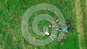 Family cycling on bikes outdoors aerial view from above, happy active parents with child have fun and relax on grass, family sport