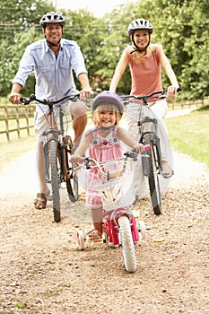 Family Cycling In Countryside Wearing Safety Helme