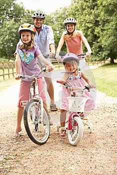 Family Cycling In Countryside Wearing Safety Helme