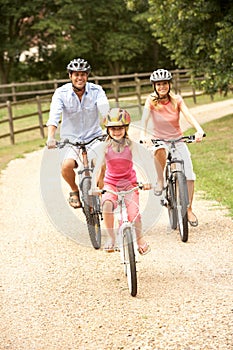 Family Cycling In Countryside Wearing Safety Helme