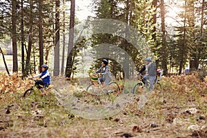Family cycling through a forest together, side view, closer