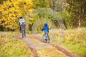 Family cycling in golden autumn park, active father and kids ride bikes, family sport and fitness