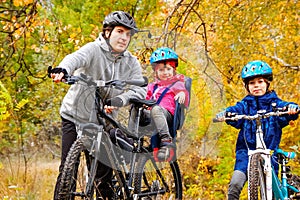 Family cycling in golden autumn park, active father and kids ride bikes, family sport and fitness