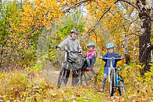 Family cycling in golden autumn park, active father and kids ride bikes, family sport and fitness with children