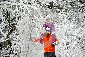 Family dad and daughter walk in the snow-covered forest in winter