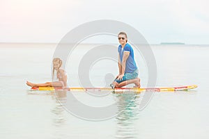 Family of dad and kid on surfboard during summer vacation