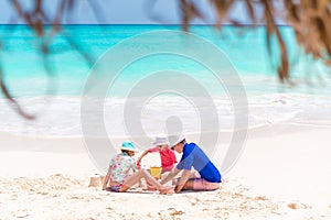 Family of dad and kids making sand castle at tropical beach