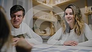 Family dad mom and daughter play board card games at the table