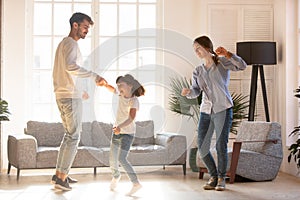 Family dancing in living room spending time on weekend together