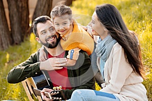 Family with daughter relaxing on a grassy hill, while little girl