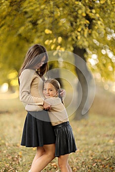 Family day. Young mom and little daughter having fun and enjoy relaxing outdoors in autumn park. Adorable child girl