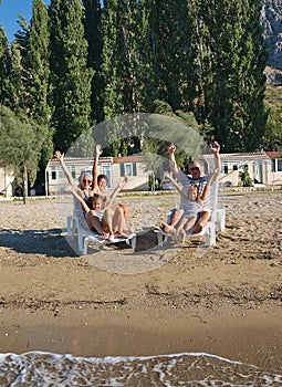 Family on deck chairs at sand beach 2