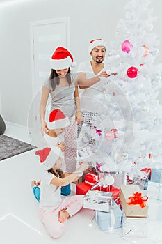 Family decorating a Christmas tree with boubles in the living-room