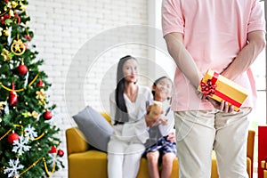 Family decorating a Christmas tree and Father giving Christmas G