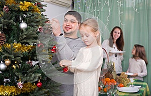 Family decorating Christmas tree at home