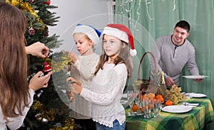 Family decorating Christmas tree at home