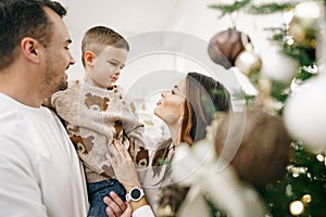 Family of 3 decorating a Christmas tree at home