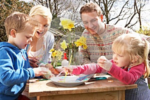 Family Decorating Easter Eggs On Table Outdoors